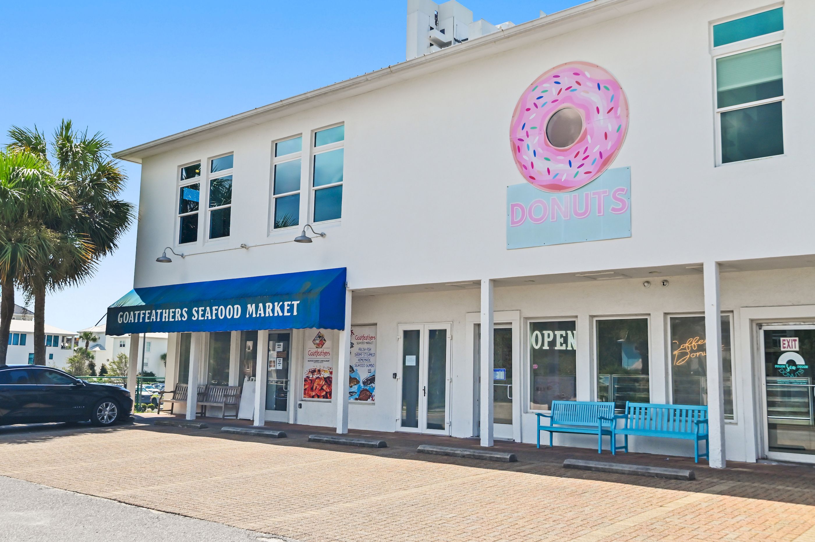 Un edifici amb un rètol que diu 'GOATFEATHERS SEAFOOD MARKET' i un rètol que diu 'DONUTS' amb una il·lustració d'un donut.