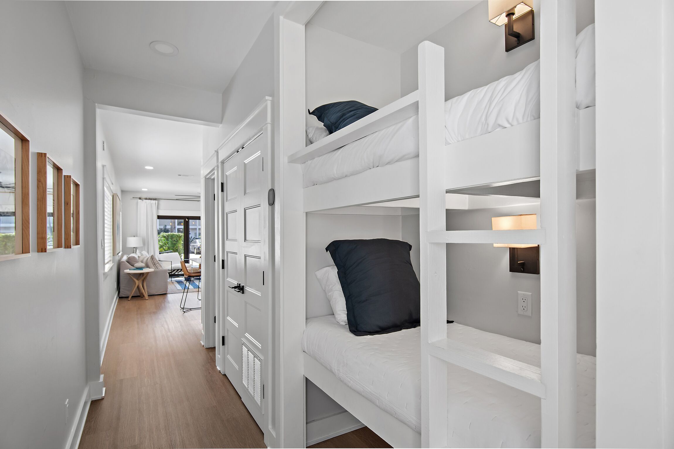 A bunk bed room with a hallway leading to a seating area.