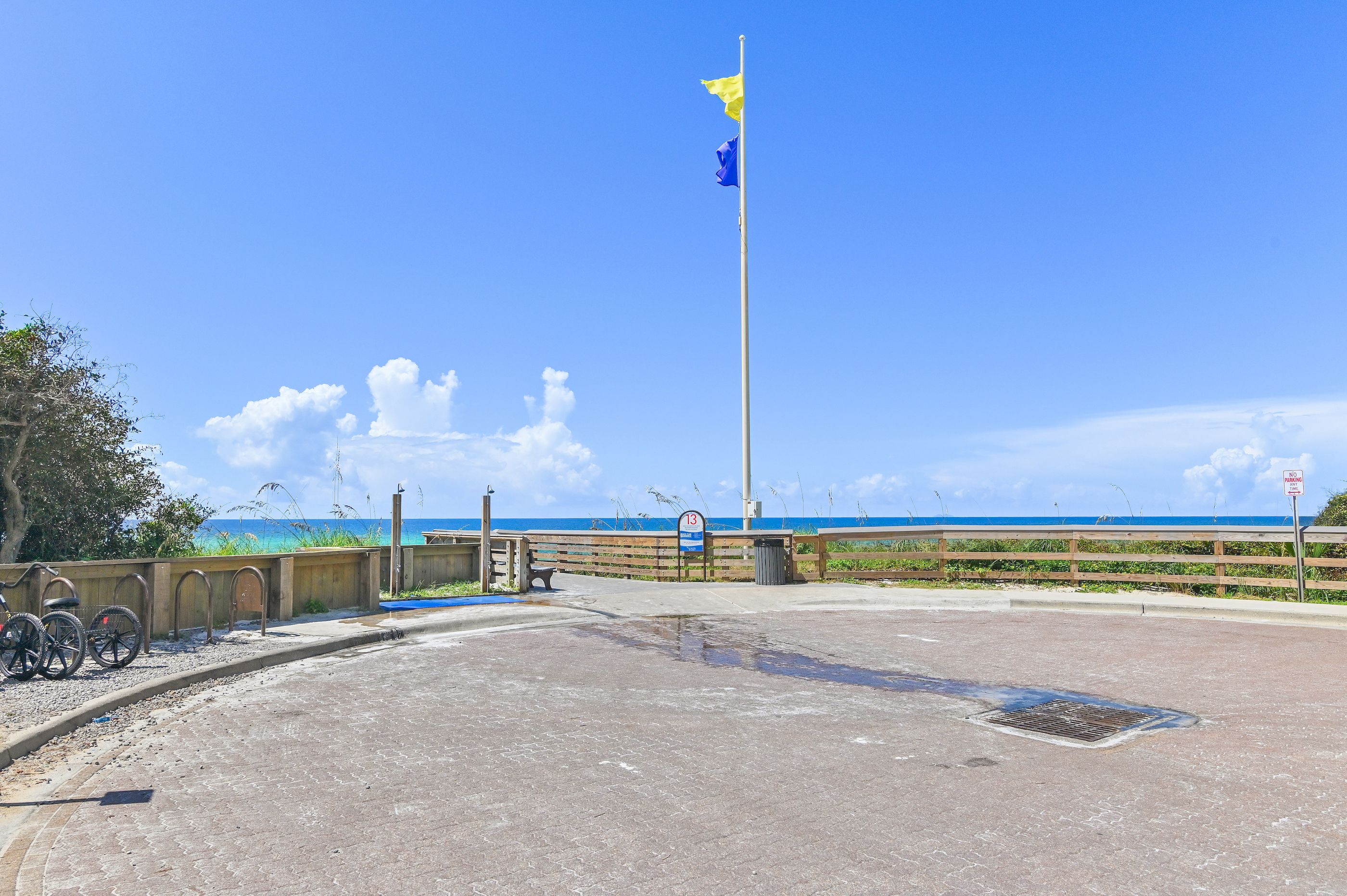 A coastal area with a flagpole, a no parking sign, and a view of the ocean.