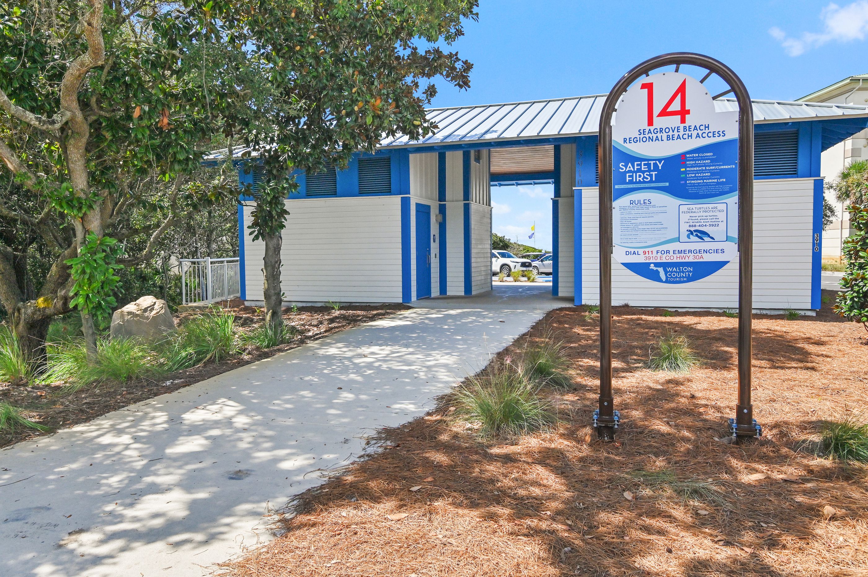 A beach access point with a sign indicating the number 14, safety information, and emergency contact details.