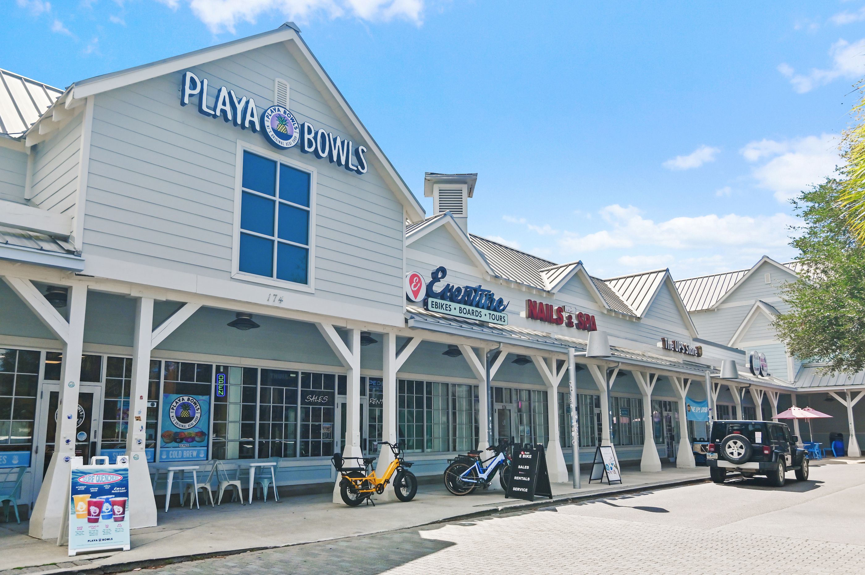 A commercial building with multiple storefronts including 'Playa Bowls', 'Centre', 'Nails & Spa', and 'The UPS Store'.