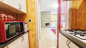 A kitchen with a red microwave, a gas stove, and a stone fireplace. - Elegant Apartment in the center of Aprica, very close to the ski slopes (Aprica)