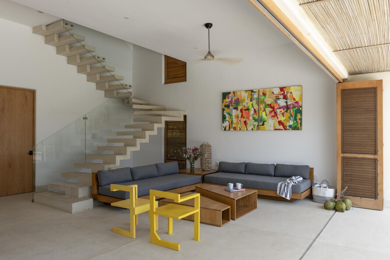 Un salon moderne avec un escalier, un canapé d’angle, une table basse et un tableau.