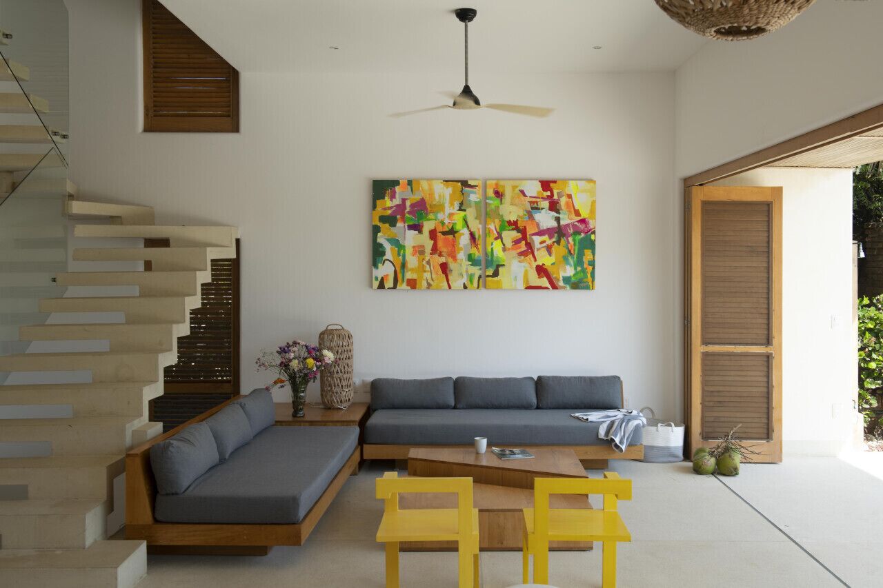 Una sala de estar moderna con un sofá empotrado, una mesa de centro de madera y una escalera con barandilla de madera.