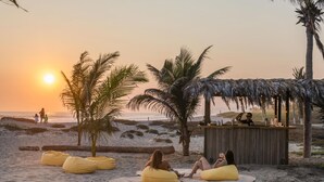 A beach scene with a bar area, palm trees, and people relaxing on bean bags.