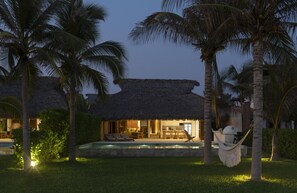 Un resort con piscina, construcciones de techo de paja y palmeras.