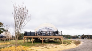 A dome-shaped structure with a wooden deck and seating area in front. - Lake Front Geodesic Dome: Hot Tub & Lake Views (Cedar Bluff)