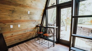 A room with wooden walls, a large window, and a chair. - Modern A-Frame Cabin: Hot Tub, TV, & Lake Views (Cedar Bluff)