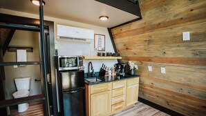 A compact kitchen with a refrigerator, microwave, and coffee maker. - Modern A-Frame Cabin: Hot Tub, TV, & Lake Views (Cedar Bluff)