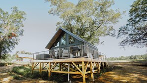 A wooden deck structure with a large window and a balcony, surrounded by trees. - Lake Front Modern Cabin: Hot Tub, TV, & Lake Views (Cedar Bluff)