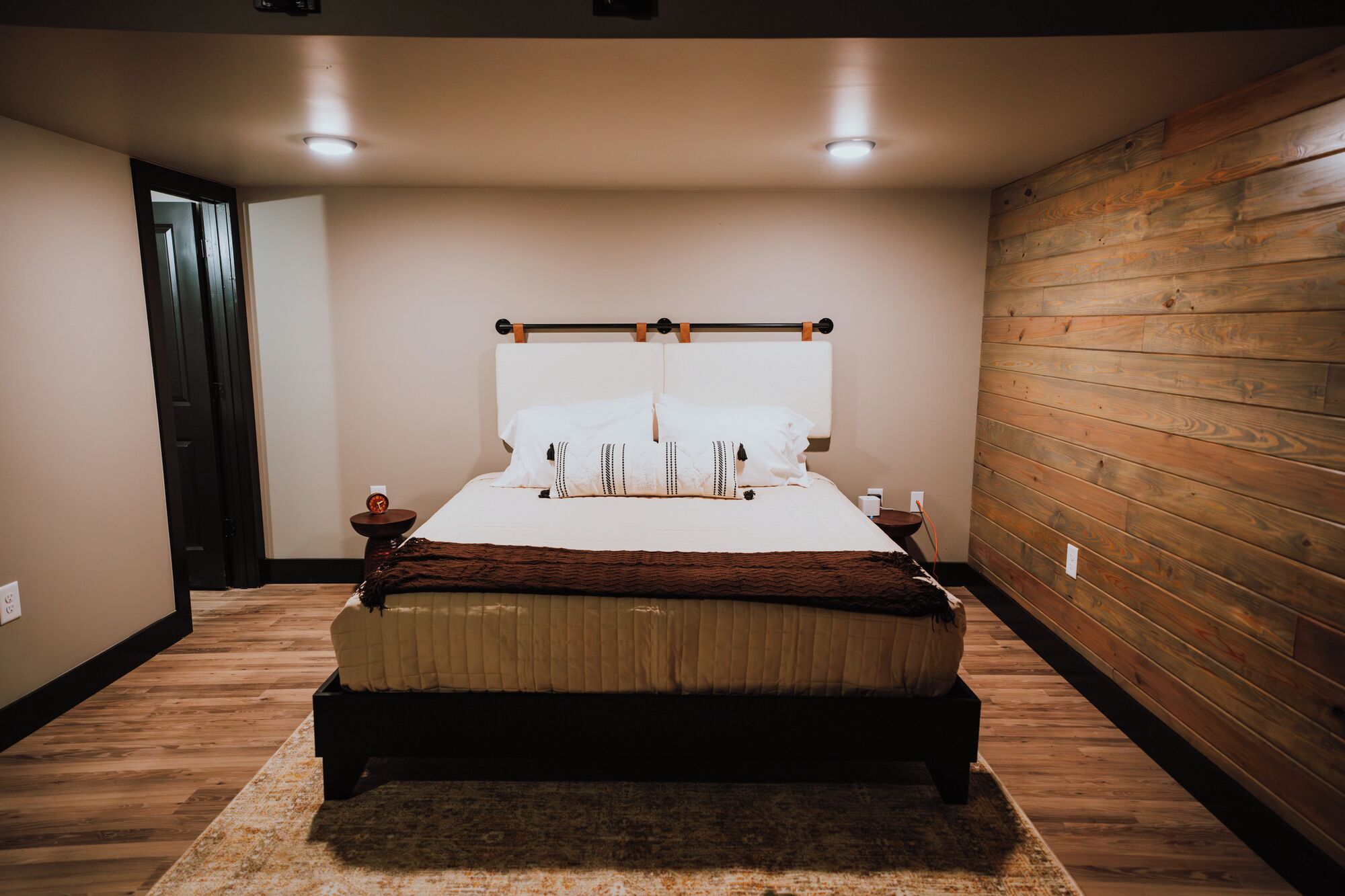 A bedroom with a bed, wooden panel walls, and a rug.