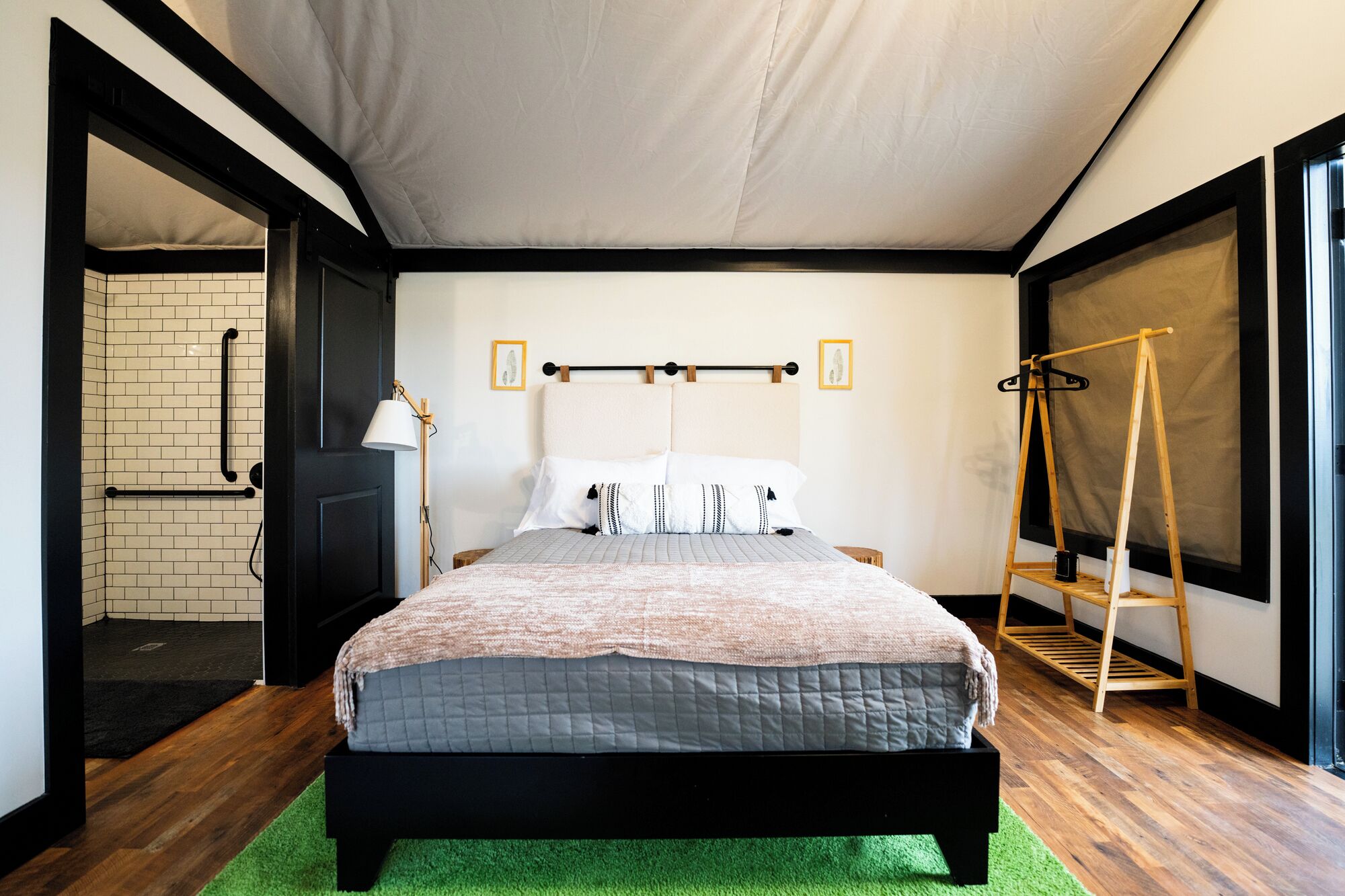 A bedroom with a bed, a wooden ladder, a lamp, and a view of a bathroom.
