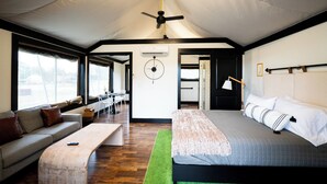 Een tent-achtige kamer met een bed, een bank, een eettafel en een plafondventilator.