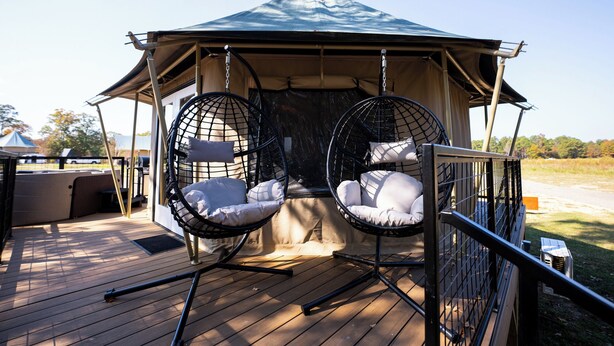 Een prieel met twee hangstoelen en een houten terras.