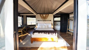 A spacious bedroom with a large bed, a hanging chair, and a view of the outdoors.