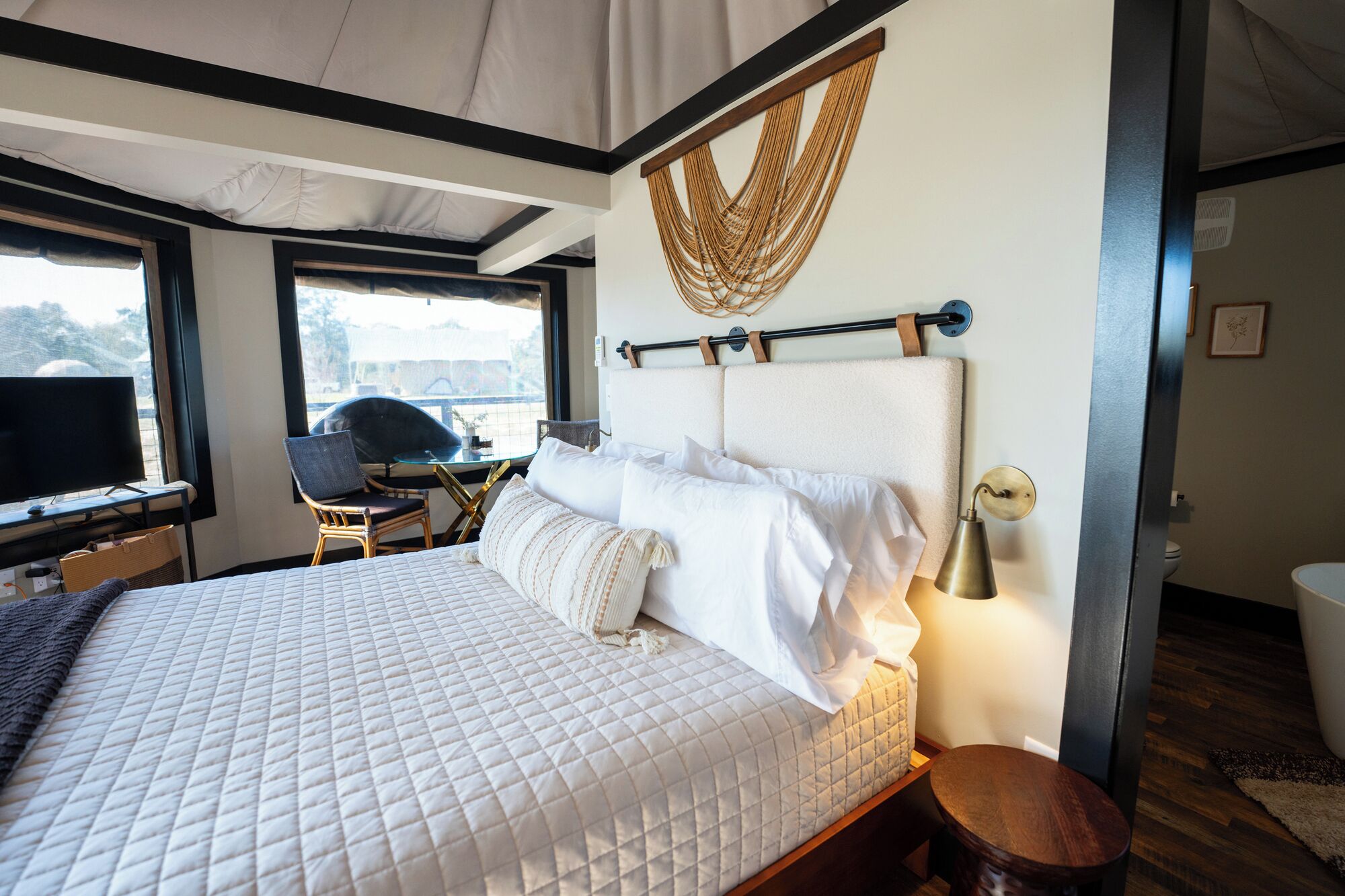 A bedroom with a large bed, a desk with a chair, and a window.