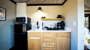 A compact kitchen with a microwave, coffee maker, and a sink.