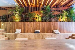 Relax in a comfortable seating area with cushioned benches and lush greenery.