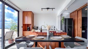Eine moderne Küche mit Holzausbau, einer zentralen Kochinsel und einem Essbereich mit grauen Polsterstühlen.