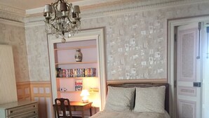 A bedroom with a wooden bed, a chandelier, a bookshelf, and a radiator. - New! Extraordinary with view of Eiffel tower, Concorde Square & Tuileries Garden (Paris)