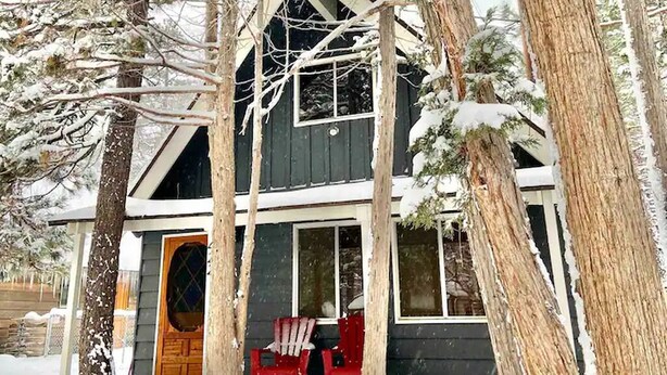 Une cabane avec une véranda, une terrasse en bois et une chaise rouge.