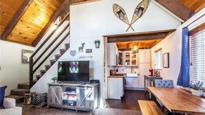 Un salon avec un téléviseur, un canapé et un escalier en bois.