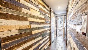 Un couloir avec un lambris en bois et une porte en verre donnant sur un espace extérieur.