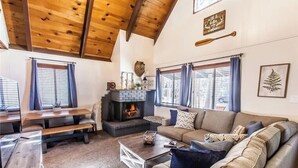 Un salon chaleureux avec une cheminée, des poutres apparentes en bois et un canapé.