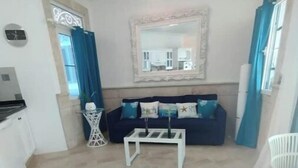 Una sala de estar con un sofá azul oscuro, una mesa de centro blanca y un espejo sobre ella.