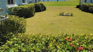 Un hotel con vista al océano, que cuenta con un césped cuidado y jardines tropicales.