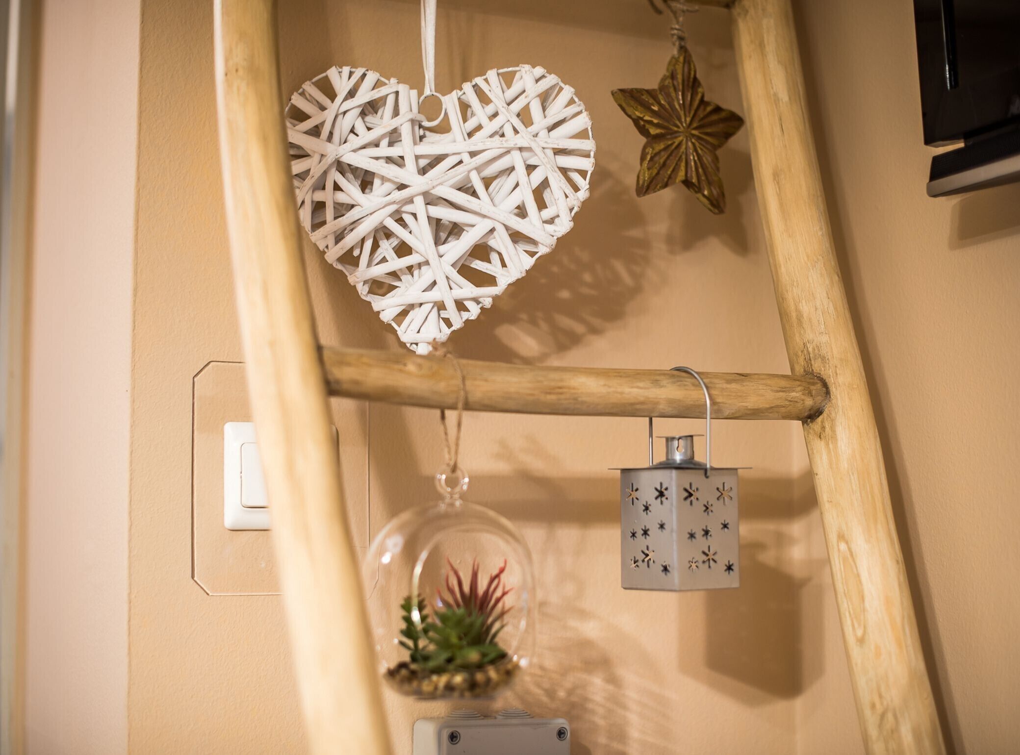 A wooden ladder with a white heart-shaped decoration and a star-shaped ornament.