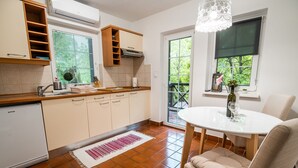 Une cuisine équipée d’un réfrigérateur, d’une cuisinière et d’un évier. On y trouve une table à manger avec des chaises et un lustre.