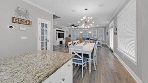 A spacious kitchen with granite countertops, white cabinetry, and a dining area with a white table and chairs. - Private Pool 🏊 Walk to Beach 🏖️ Family Tides 🏝️ (Destin)