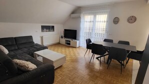 Un soggiorno moderno con divano, tavolino, televisore e zona pranzo.