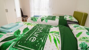 Un dormitorio con dos camas, una silla, un armario y una ventana con cortinas.