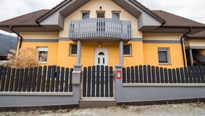 A two-story building with a balcony, a wooden fence, and a door with a window.