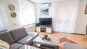A living room with a sofa, coffee table, TV, and a painting on the wall.