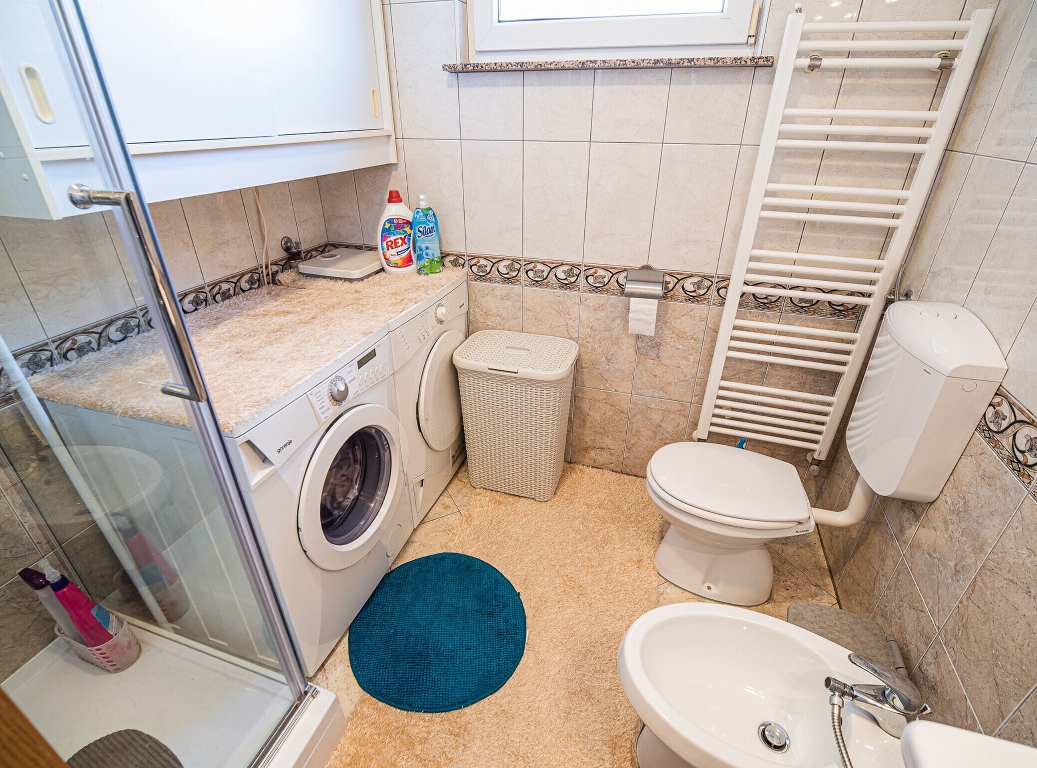Baño compacto con lavadora, inodoro, lavabo y zona de ducha.
