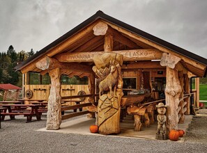 A wooden cabin with a rustic design, featuring a large carved elk head and a sign that reads "Pivovarna Lasko". - Visnja Gora Meadow Hideaway with Terrace - Classic One Bedroom Apartment with Terrace (Visnja Gora)