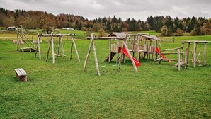 A playground with wooden structures and a red slide in a grassy field. - Visnja Gora Meadow Hideaway with Terrace - One Bedroom Cottage with Terrace (Visnja Gora)