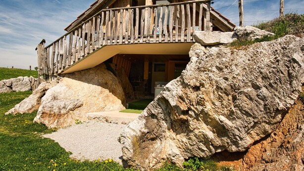 A wooden chalet with a balcony, built on a rocky hillside. - Visnja Gora Meadow Hideaway with Terrace - One Bedroom Cottage with Terrace (Visnja Gora)