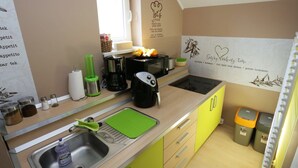 Uma cozinha compacta com pia, cafeteira, micro-ondas e torradeira. Há armários e uma janela acima da pia.