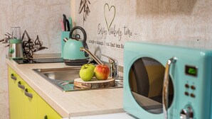 A kitchen with a teal microwave, a sink, and a wooden cutting board with apples.