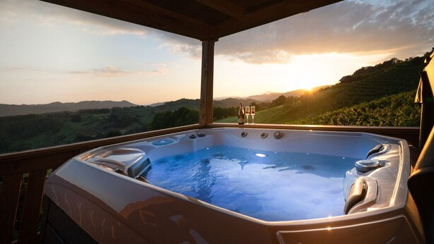 A hot tub with a scenic view of hills and a sunset.