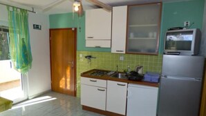 A compact kitchen with a gas stove, a refrigerator, and a microwave.