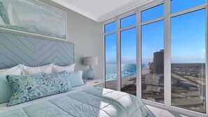 A bedroom with a large window offering a view of the ocean and cityscape. - Luxury 4BR Beachfront Corner Unit, Panoramic Gulf Views, Lazy River, Indoor Pool (Orange Beach)
