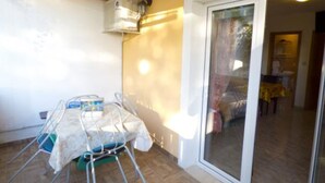 Ein kleiner, abgeschlossener Balkon mit Tisch und Stühlen, einem Fenster und einer Tür zu einem Innenbereich.
