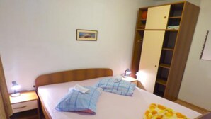 Ein Schlafzimmer mit Bett, Nachttisch, Kleiderschrank und einem gerahmten Bild an der Wand.