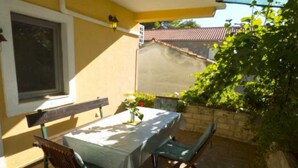 Patio esterno con tavolo e sedie, una panchina e una pianta in vaso.