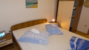 Una camera da letto con un letto, un comodino, una lampada, un armadio e un quadro appeso al muro.